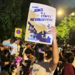 (बिहीबार, जुलाई २३, २०२६ मा भारतको नयाँ दिल्लीमा ककरोच जनता पार्टीको चलिरहेको विरोध आन्दोलनको एक भागको रूपमा शैक्षिक सुधारको माग गर्दै गरिएको प्रदर्शनको क्रममा "हरेक मजाक एउटा सानो क्रान्ति हो" भन्ने सन्देश लेखिएको प्लेकार्ड बोकेका एक प्रदर्शनकारी। एपी फोटो: भेर्डा सब्जवारी)