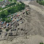 (बुधबार, २६ अगस्ट २०२६ मा नेपालको नुवाकोट जिल्लामा आएको आकस्मिक बाढीपछि त्रिशूली नदीको उर्लिएको र मलबाहरूले भरिएको किनारनजिकै क्षतिग्रस्त घरहरू जोखिमपूर्ण अवस्थामा उभिएका छन्। (एपी तस्बिर: निरञ्जन श्रेष्ठ)